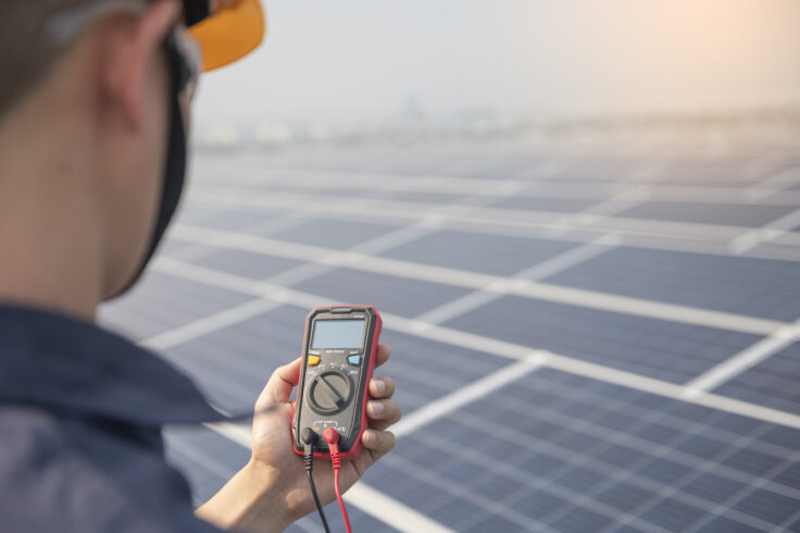 Engineer holding sets the operation of the solar panel on the roof of the building to work at full efficiency.using solar cells is energy saving. renewable energy concepts.