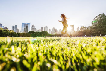 Girl runs in front of manhattan skyline in central park